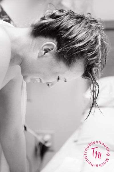 A woman in a hospital setting is leaning forward with a pained expression during labor, illustrating first-time labor challenges and the importance of labor and delivery tips and tools.