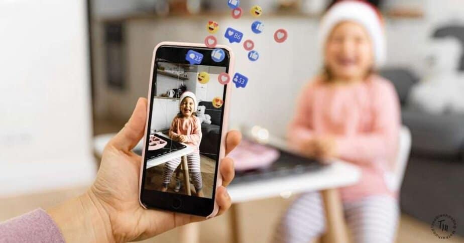 Sharenting kids on social media. Image of woman taking photo of child on cell phone, social media icons above phone.
