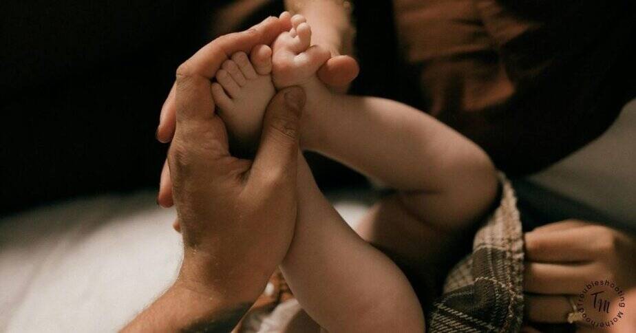 Boho Baby Names. Close-up photo of a parent gently holding a baby’s feet and legs, conveying a soft, intimate moment that represents choosing meaningful boho baby names for boys and girls.