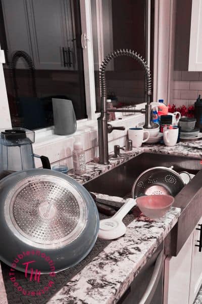 messy kitchen sink with dishes, cups, and clutter in a busy family home