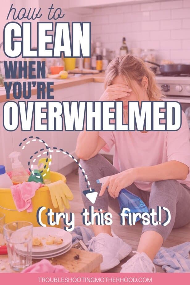 A tired woman sitting on the kitchen floor surrounded by cleaning supplies, showing how to clean when you’re overwhelmed and mentally exhausted.