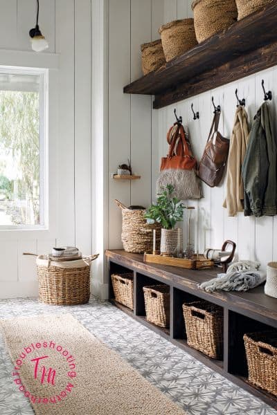 Bright entryway with wall hooks, backpacks, jackets, and shoe baskets showing a simple home reset system to keep a messy house organized