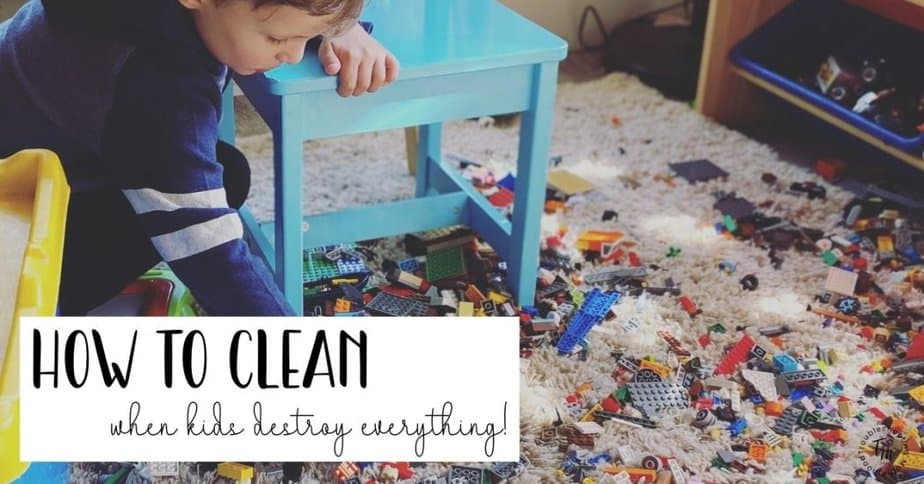 messy playroom floor covered in toys and legos while child plays, representing cleaning when kids destroy everything